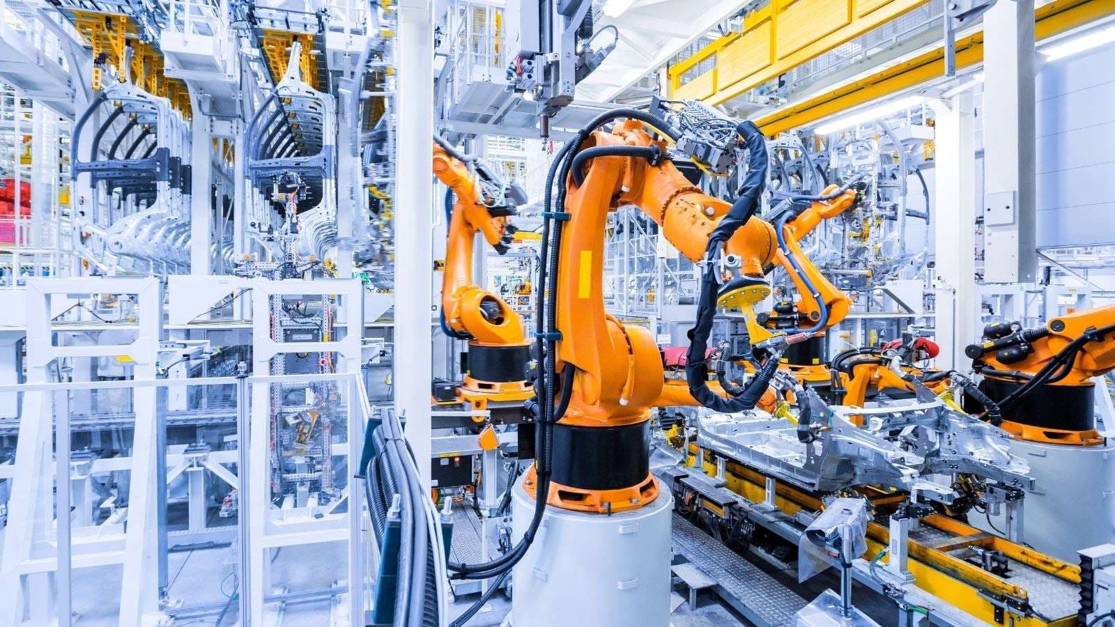 Otomotiv üretim hattında turuncu robot kolları gövde kaynağı yapıyor